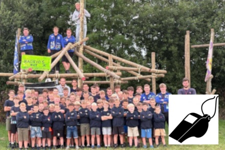 Groepsfoto van alle leden en leiding voor een zelfgebouwde constructie.